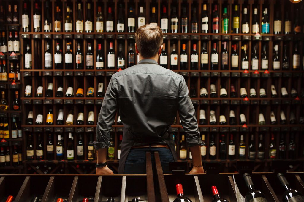 Bartender looking at a wine cellar full of bottles 