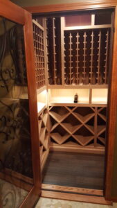 Open wooden door into a small wine room with a single bottle on display