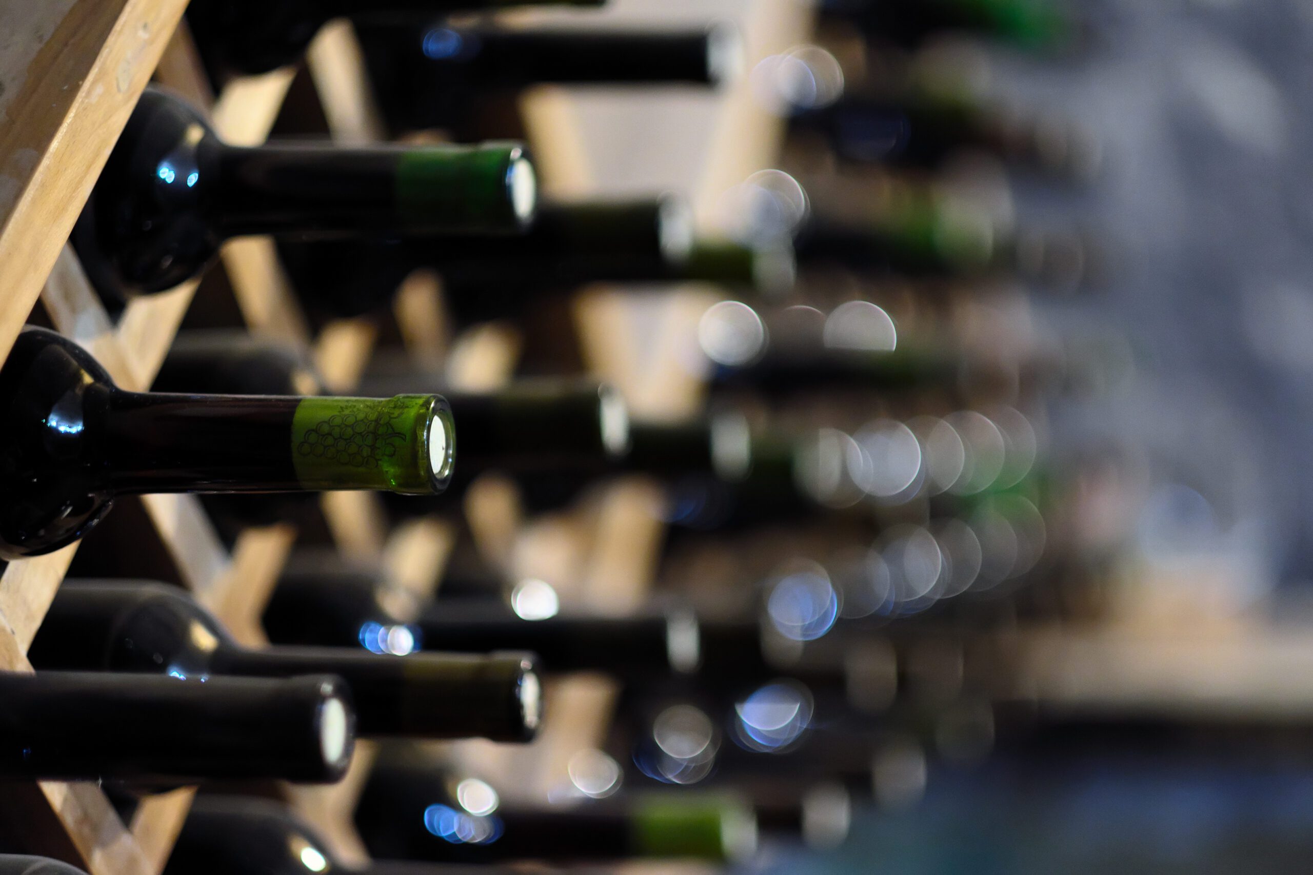 Resting wine bottles stacked on wooden racks in cellar